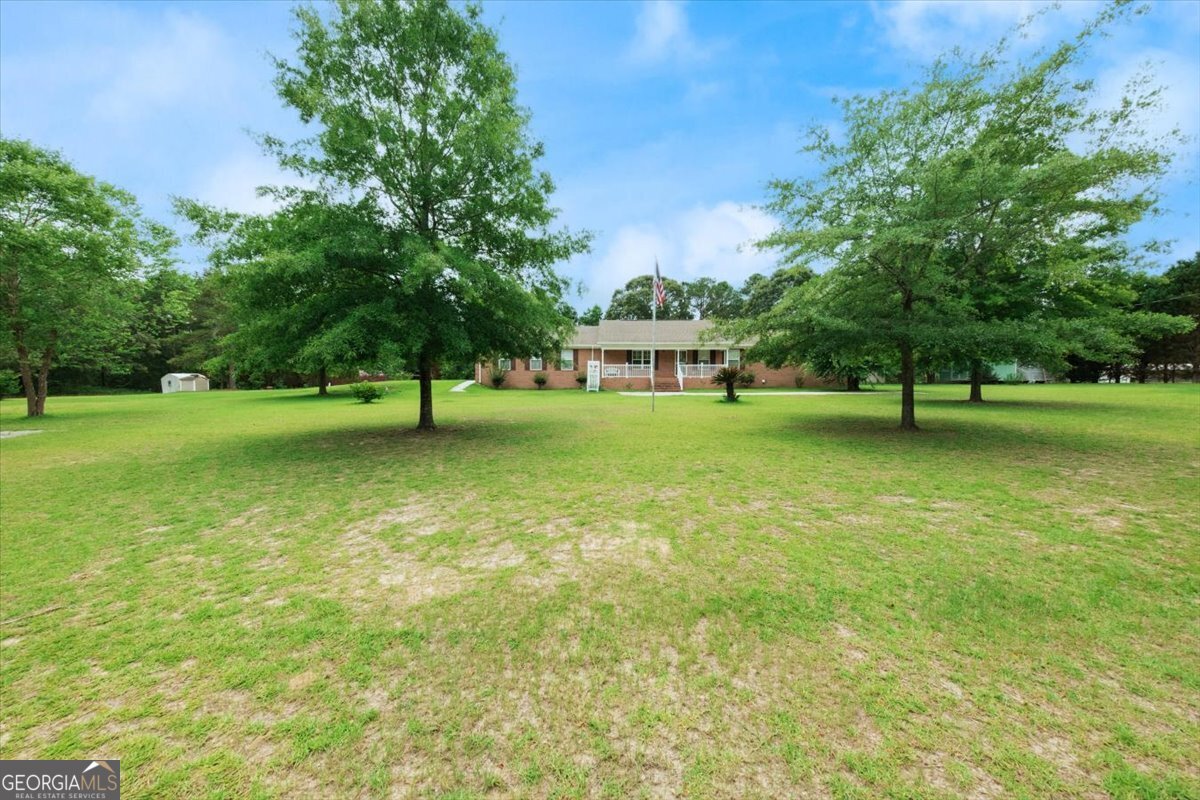 a view of pool with a big yard and large trees