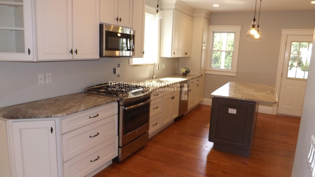 a kitchen with granite countertop white cabinets and window