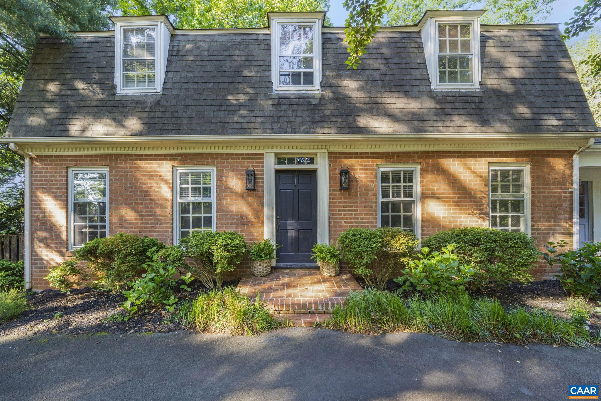 a view of a brick house with plants and large tree