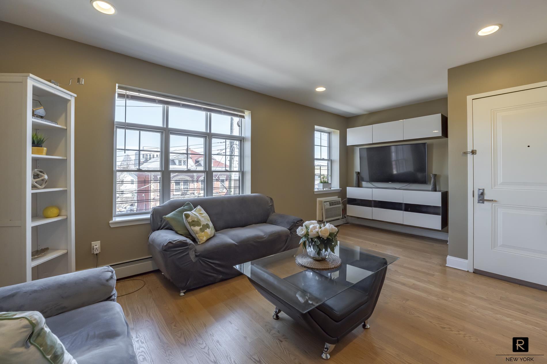 a living room with furniture wooden floor and a floor to ceiling window