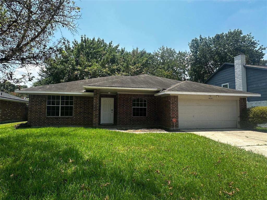 a front view of house with yard and trees in the background