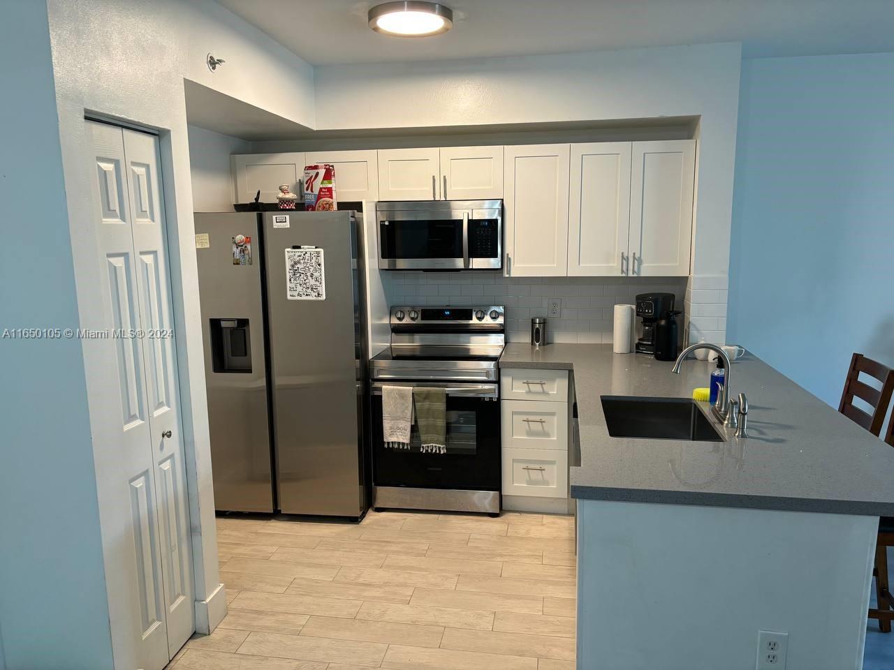 a kitchen with stainless steel appliances a refrigerator sink and microwave