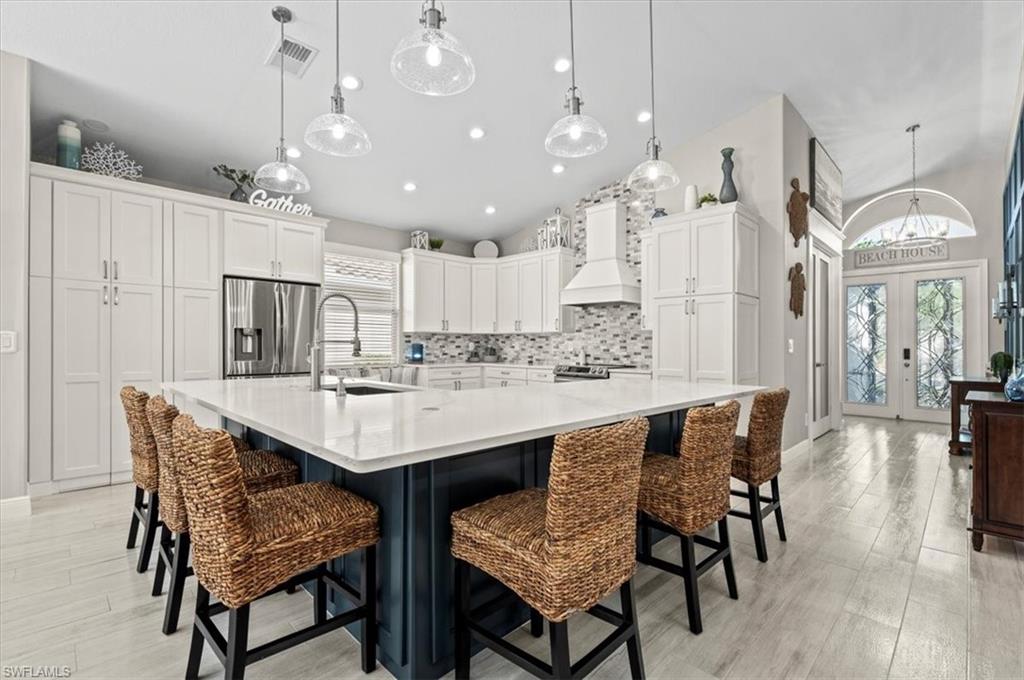 a kitchen with kitchen island a dining table chairs sink and cabinets