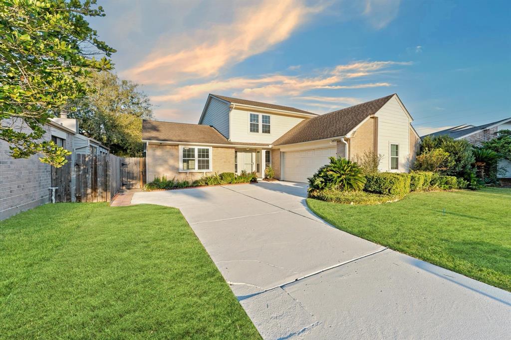 Step up to a welcoming entrance with a wide driveway and a perfectly manicured front lawn.