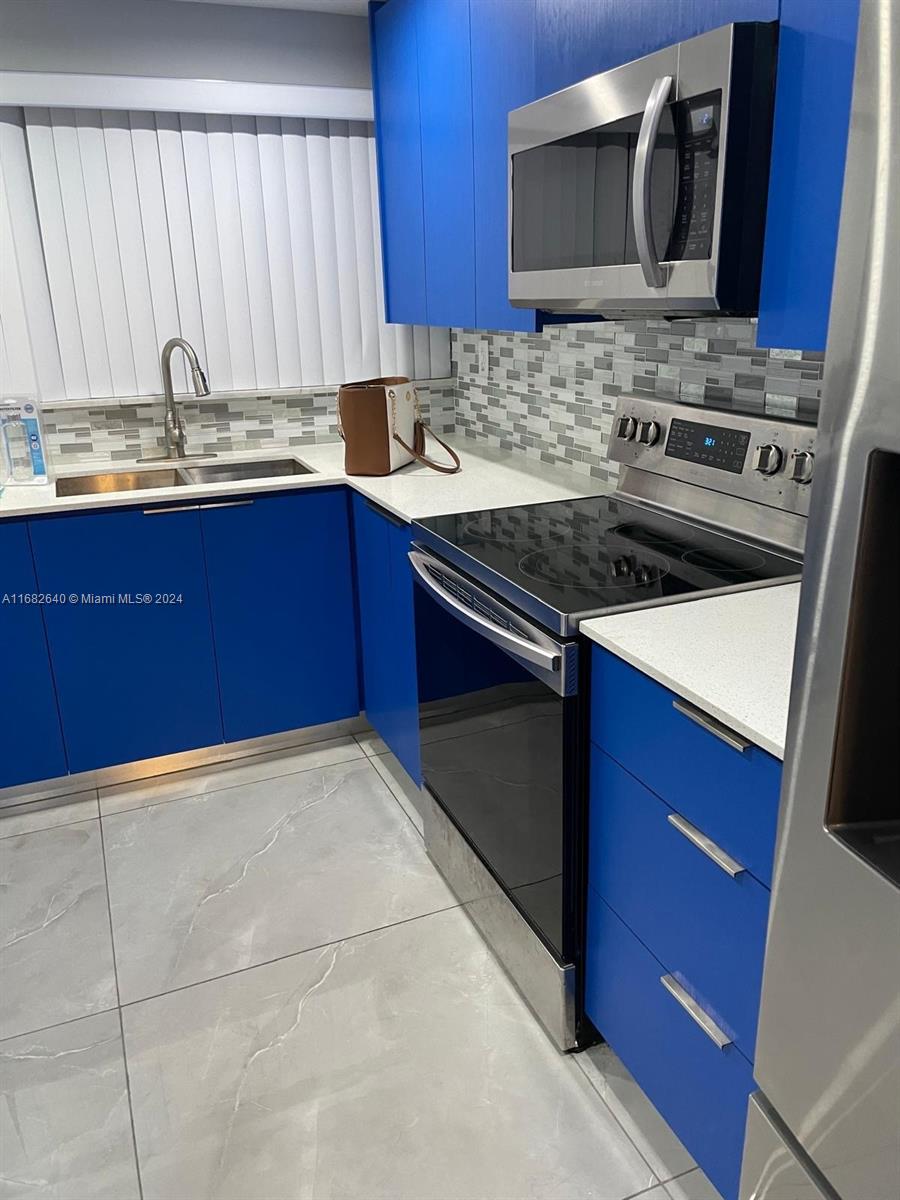 a kitchen with stainless steel appliances a stove microwave and sink