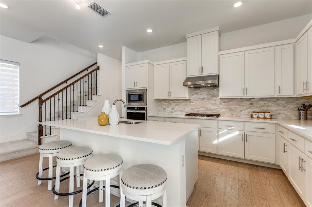 a kitchen with stainless steel appliances a white table and chairs in it