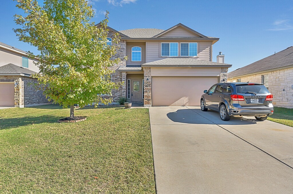 a view of a house with a small yard and large parking space