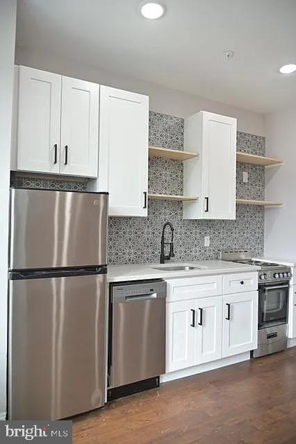 a kitchen with stainless steel appliances granite countertop a refrigerator a stove a sink and white cabinets