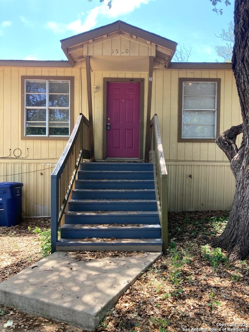 a view of a house with a small yard and wooden fence and a large window