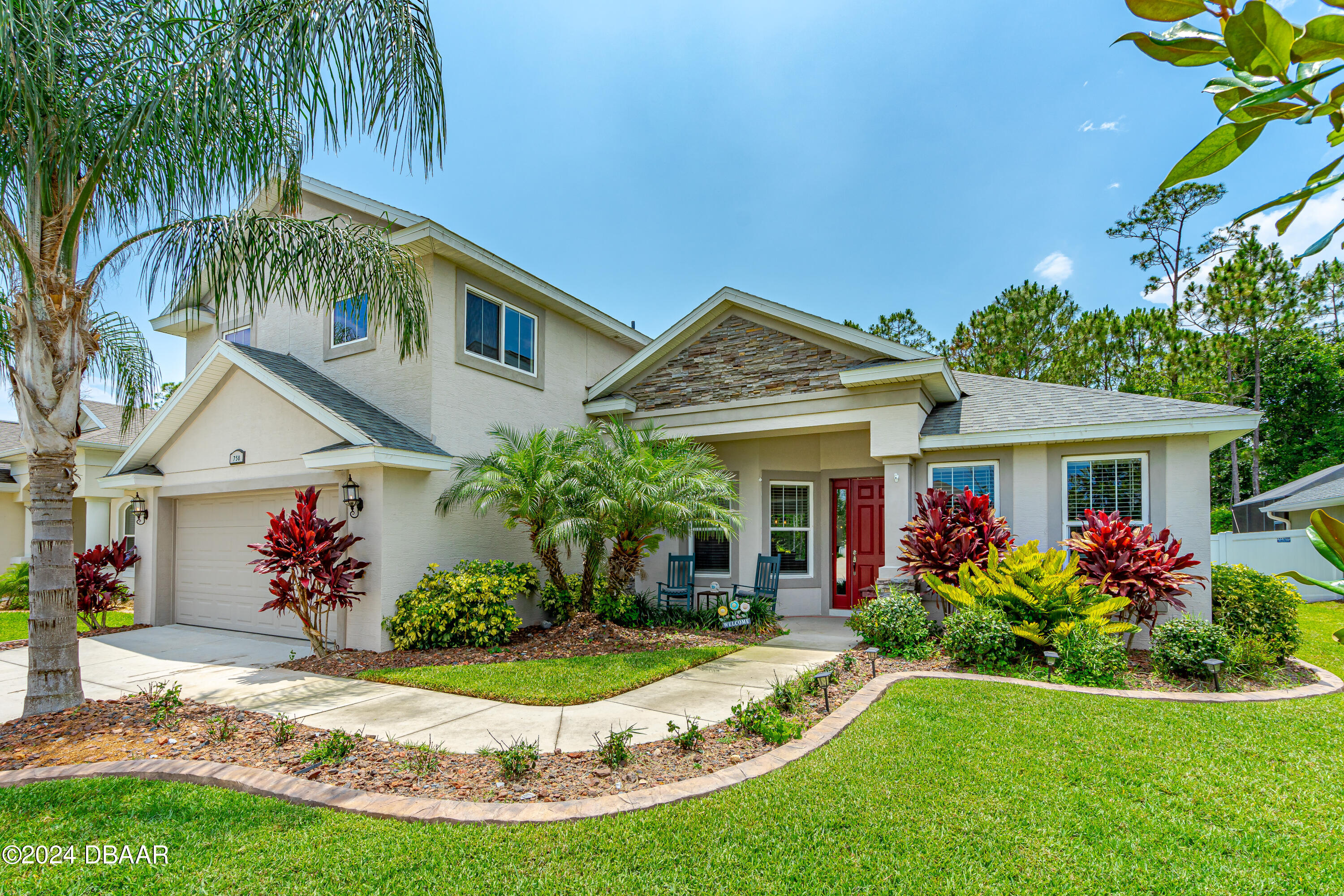 a front view of a house with a yard and potted plants