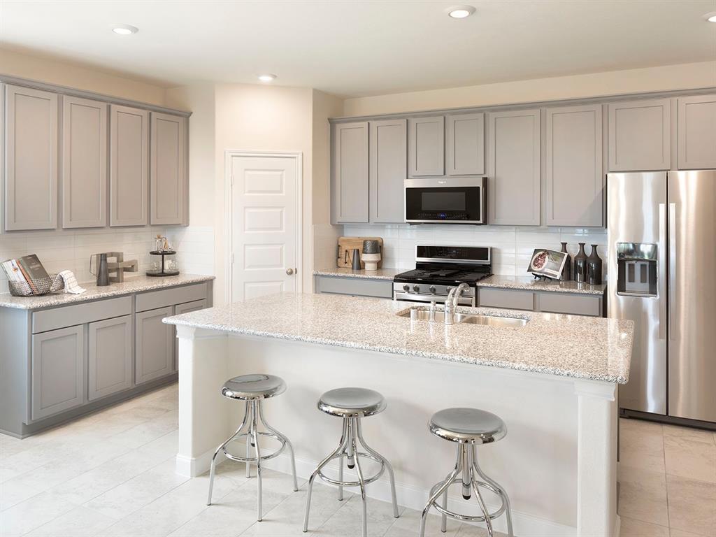 a kitchen with stainless steel appliances a stove a sink a microwave a refrigerator and cabinets