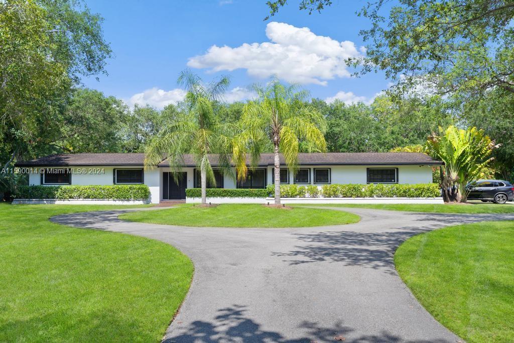 a front view of a house with garden and trees