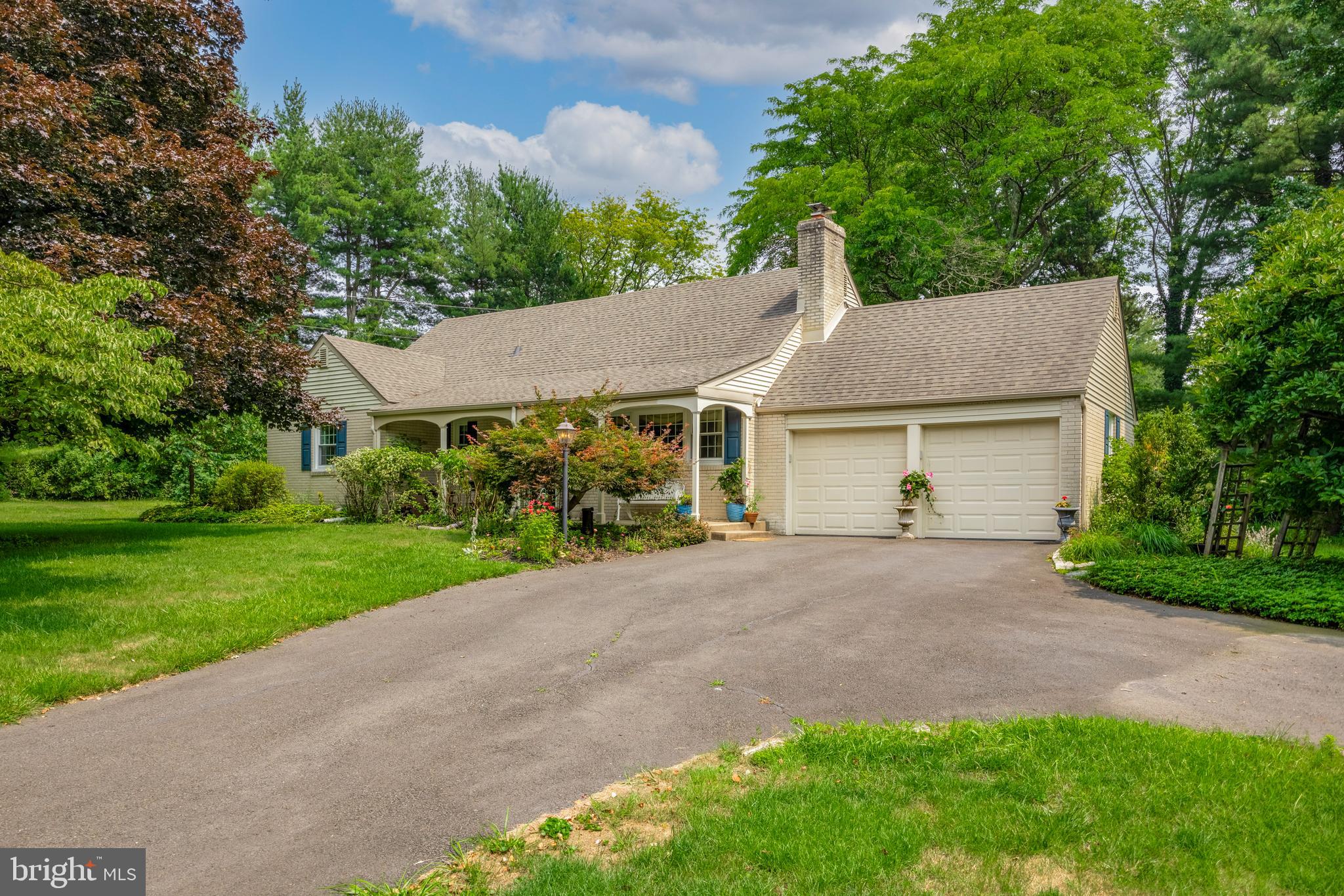 a view of a house with a yard plants and large tree