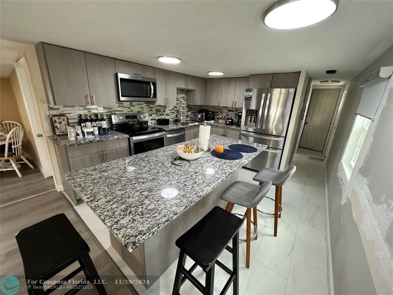 a kitchen with stainless steel appliances granite countertop a table chairs sink refrigerator and microwave