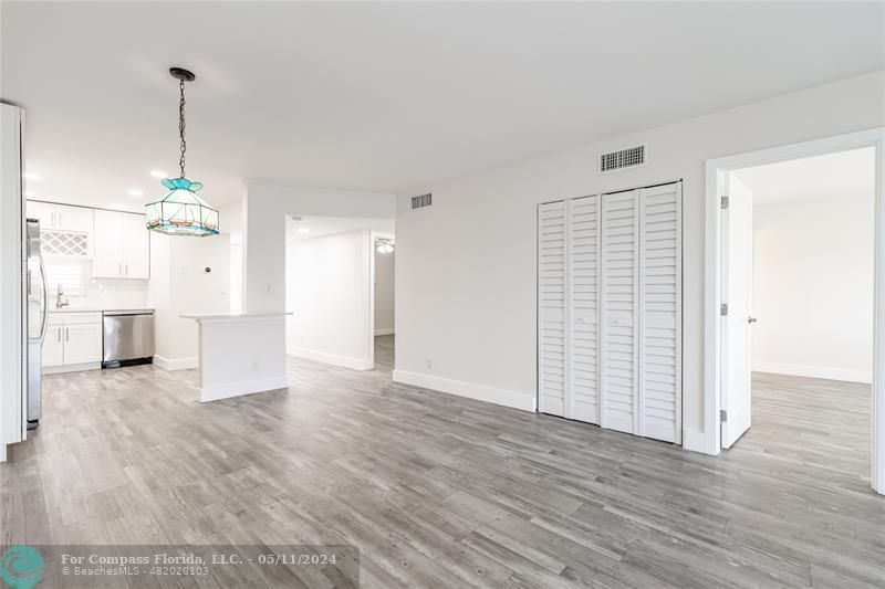 a view of empty room with wooden floor and kitchen view