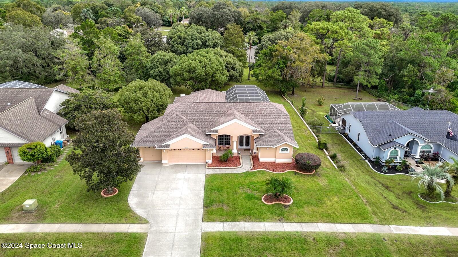 an aerial view of residential houses with outdoor space and trees