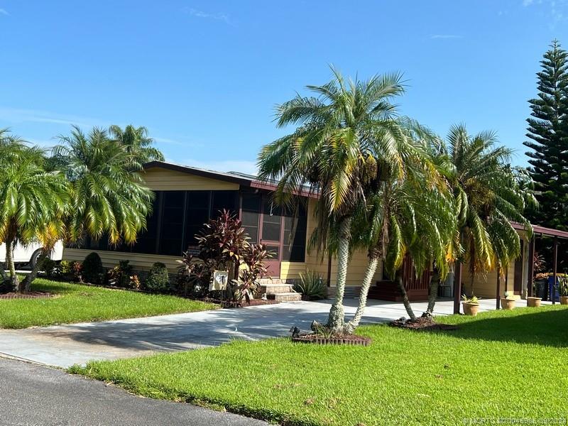 a view of a house with a yard and palm trees