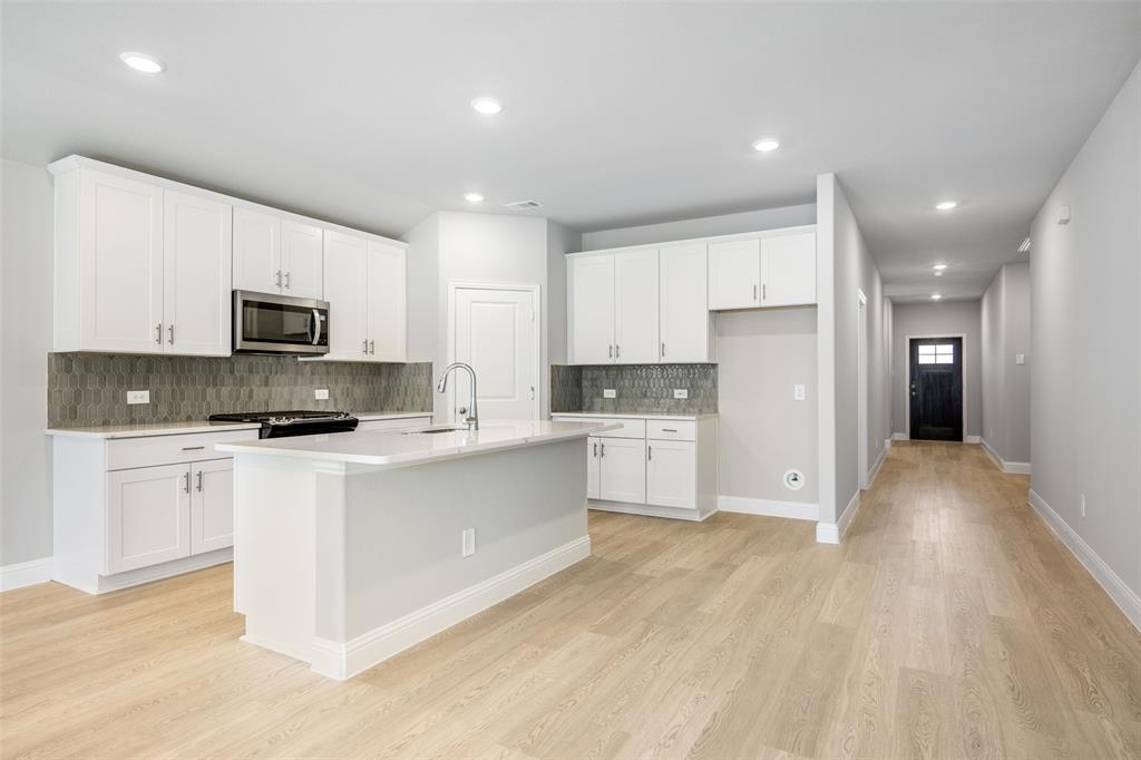 a large kitchen with cabinets wooden floor and stainless steel appliances