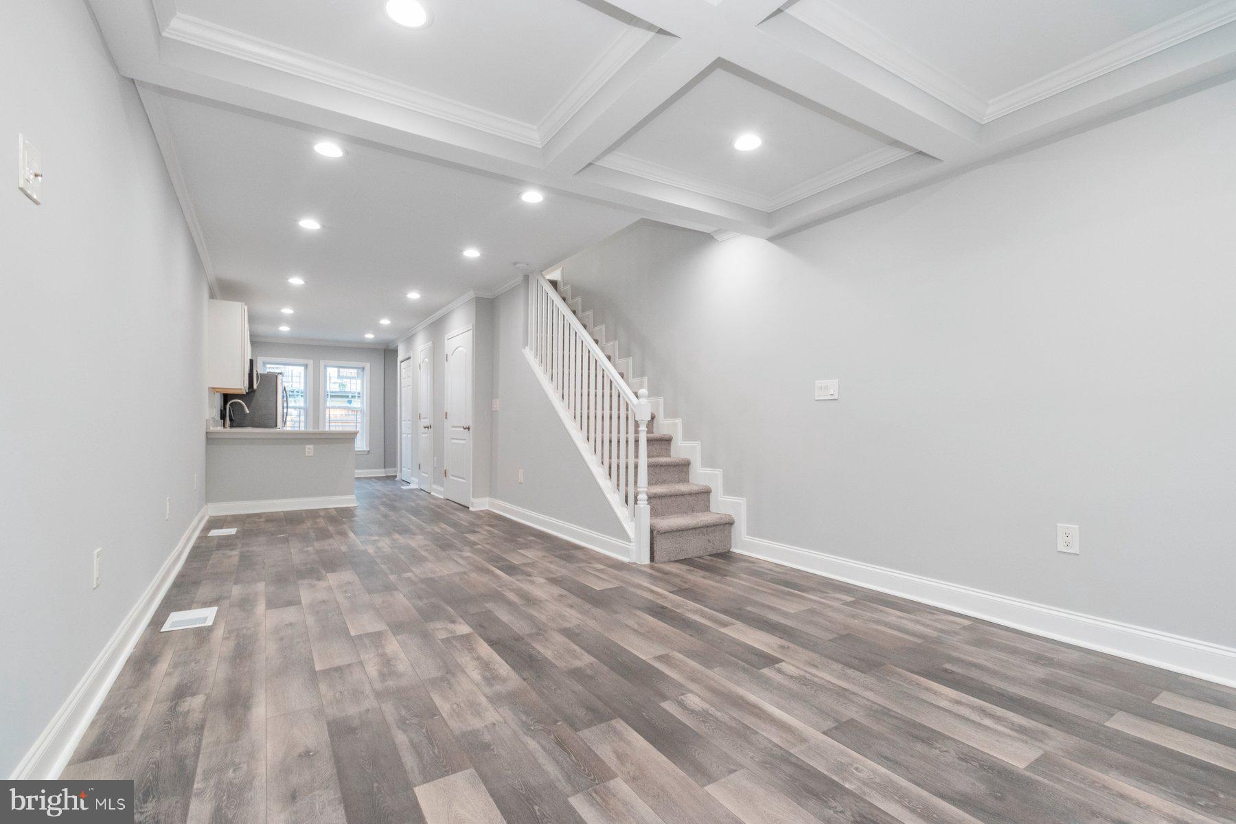 a view of an empty room with wooden floor and stairs