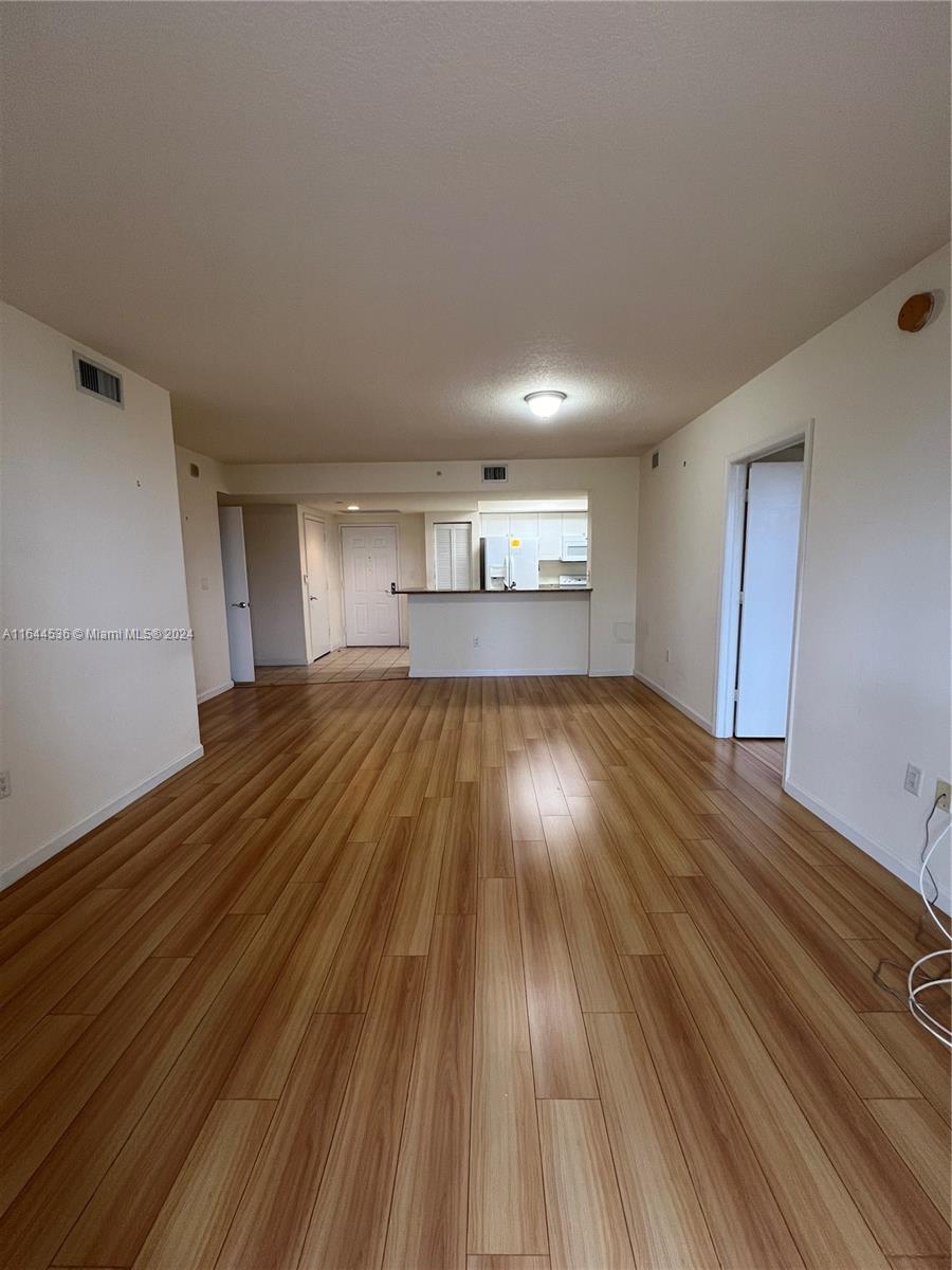 a view of an empty room with window and wooden floor