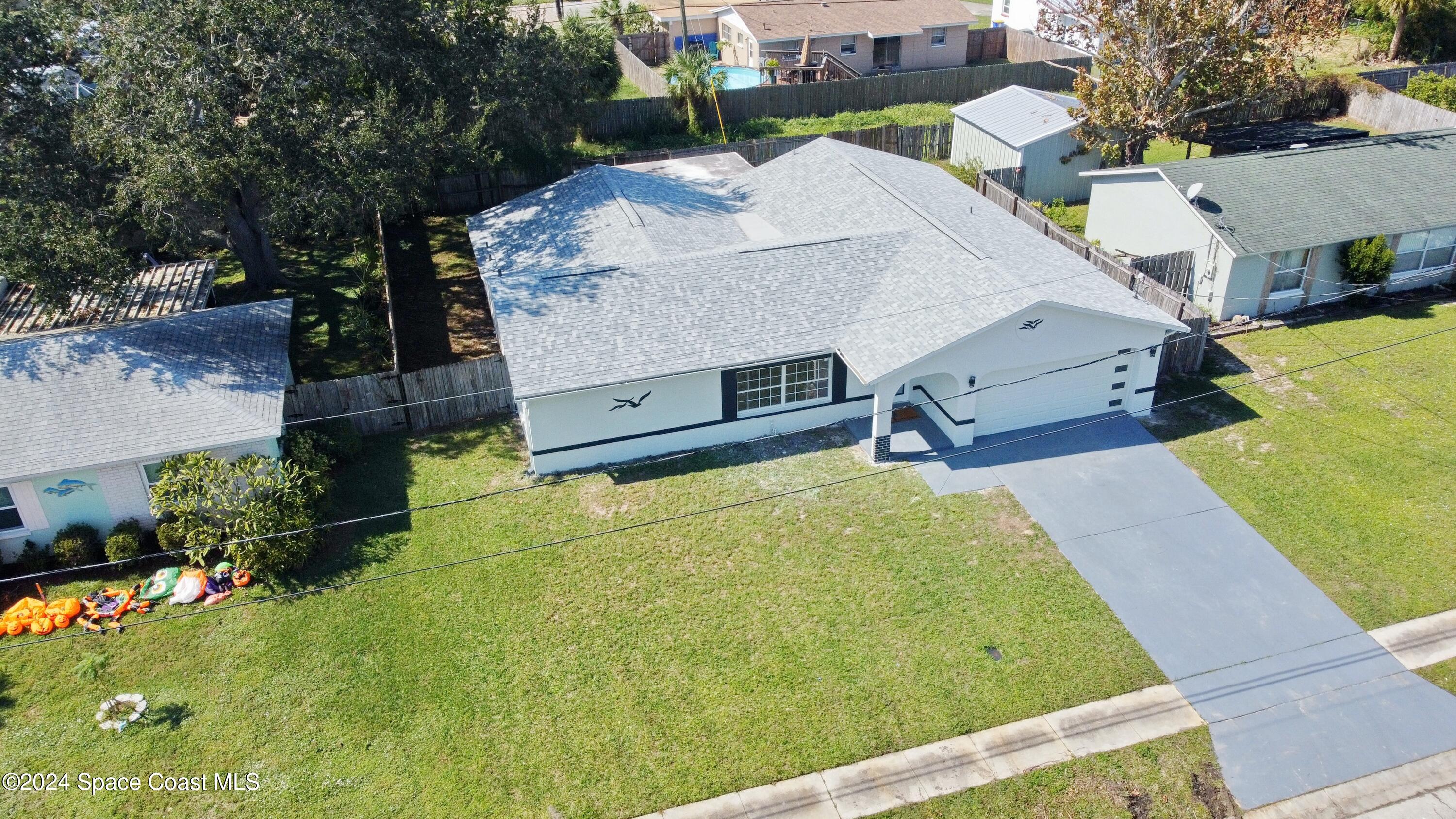 an aerial view of a house with swimming pool and large trees