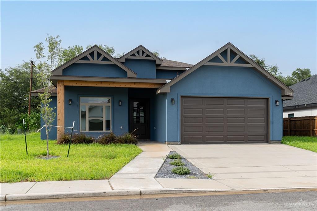 View of front of property featuring a garage and a front lawn