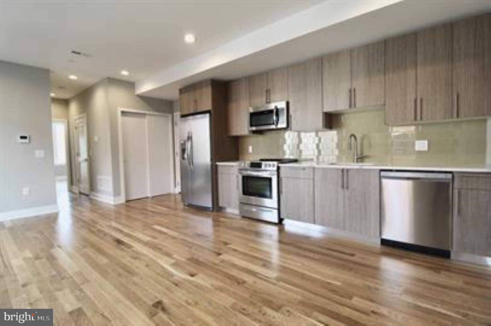 a kitchen with stainless steel appliances a sink cabinets and wooden floor