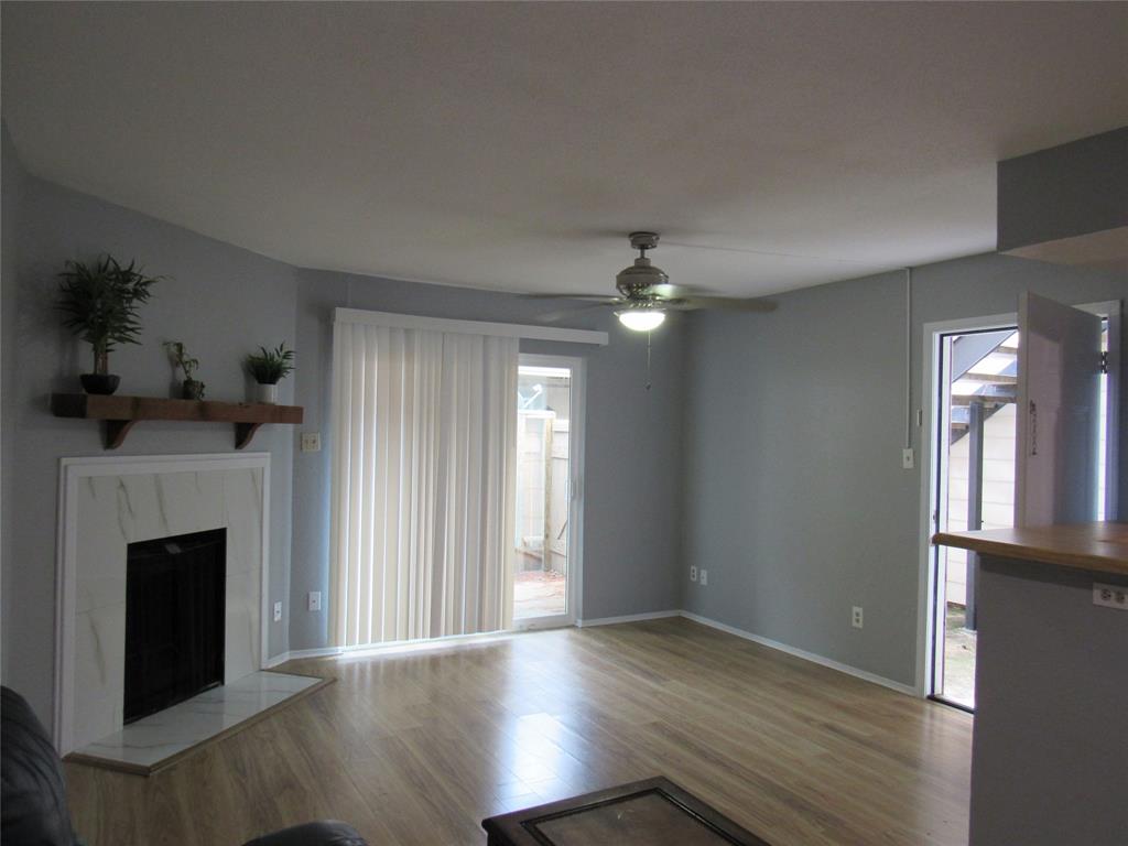 a view of an empty room with wooden floor fireplace and a window