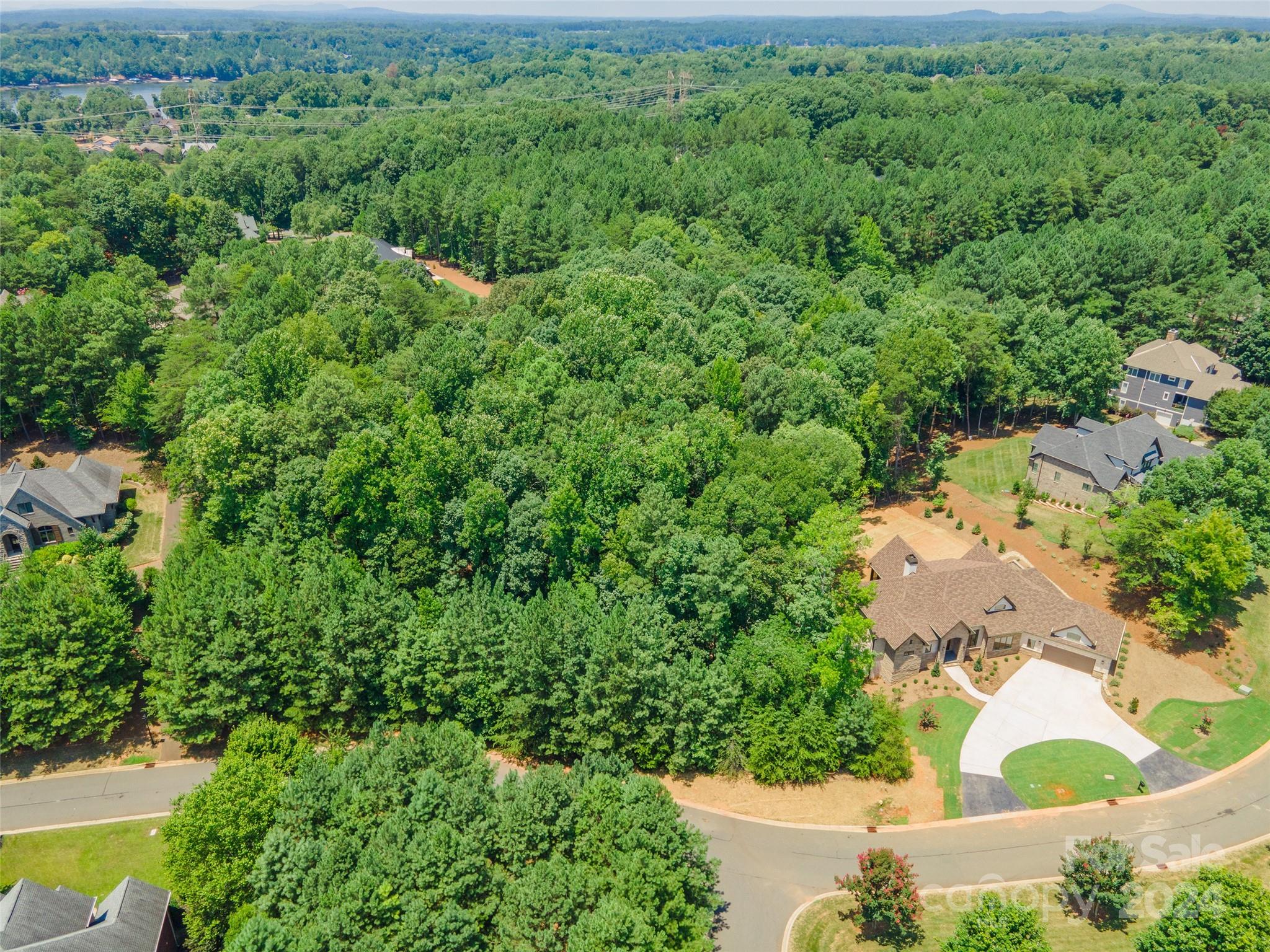 an aerial view of residential house with outdoor space and trees all around