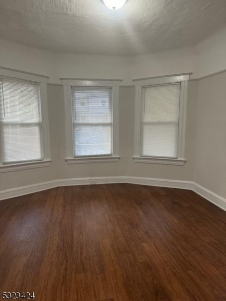 a view of an empty room with wooden floor and window