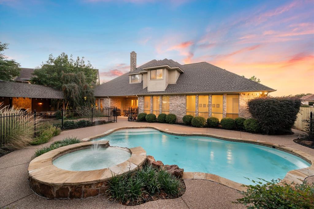 Pool at dusk featuring an in ground hot tub and pool water feature