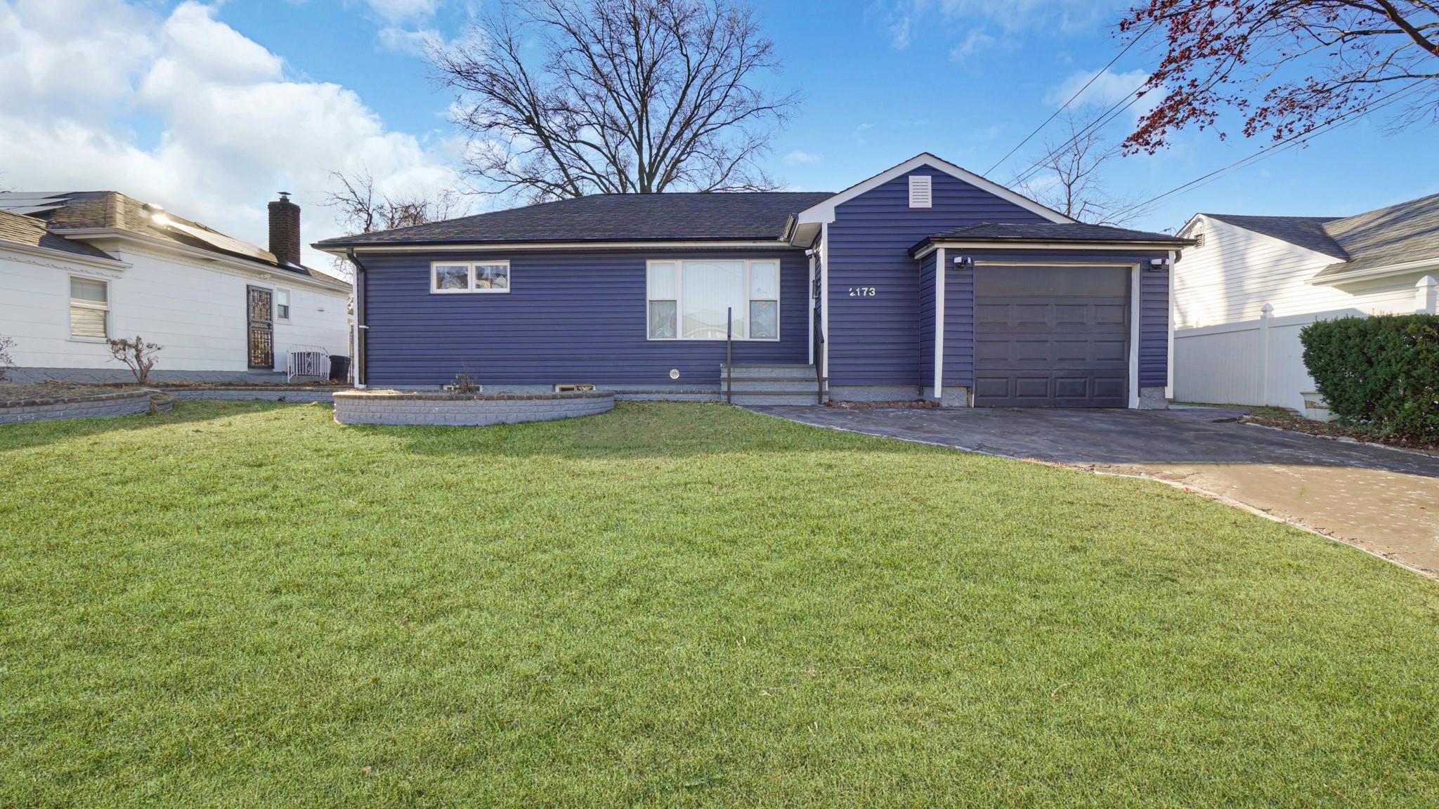 Ranch-style house featuring a front yard and a garage