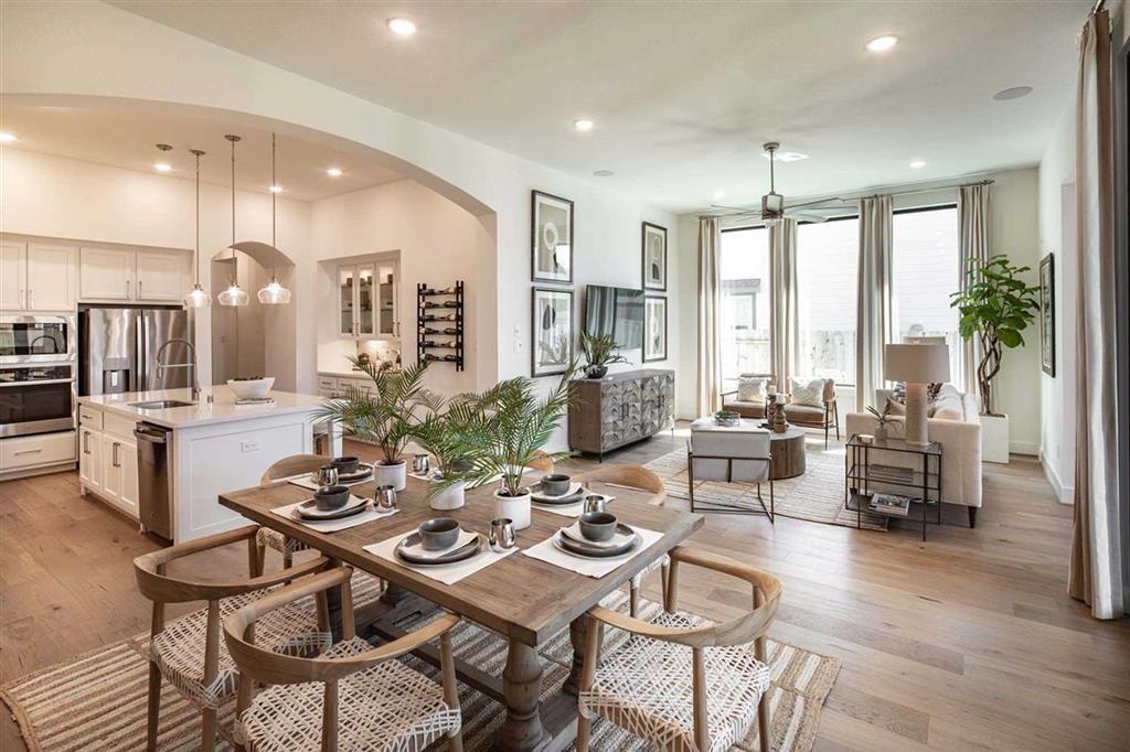 a view of a dining room and livingroom with furniture wooden floor a rug a fireplace and a chandelier