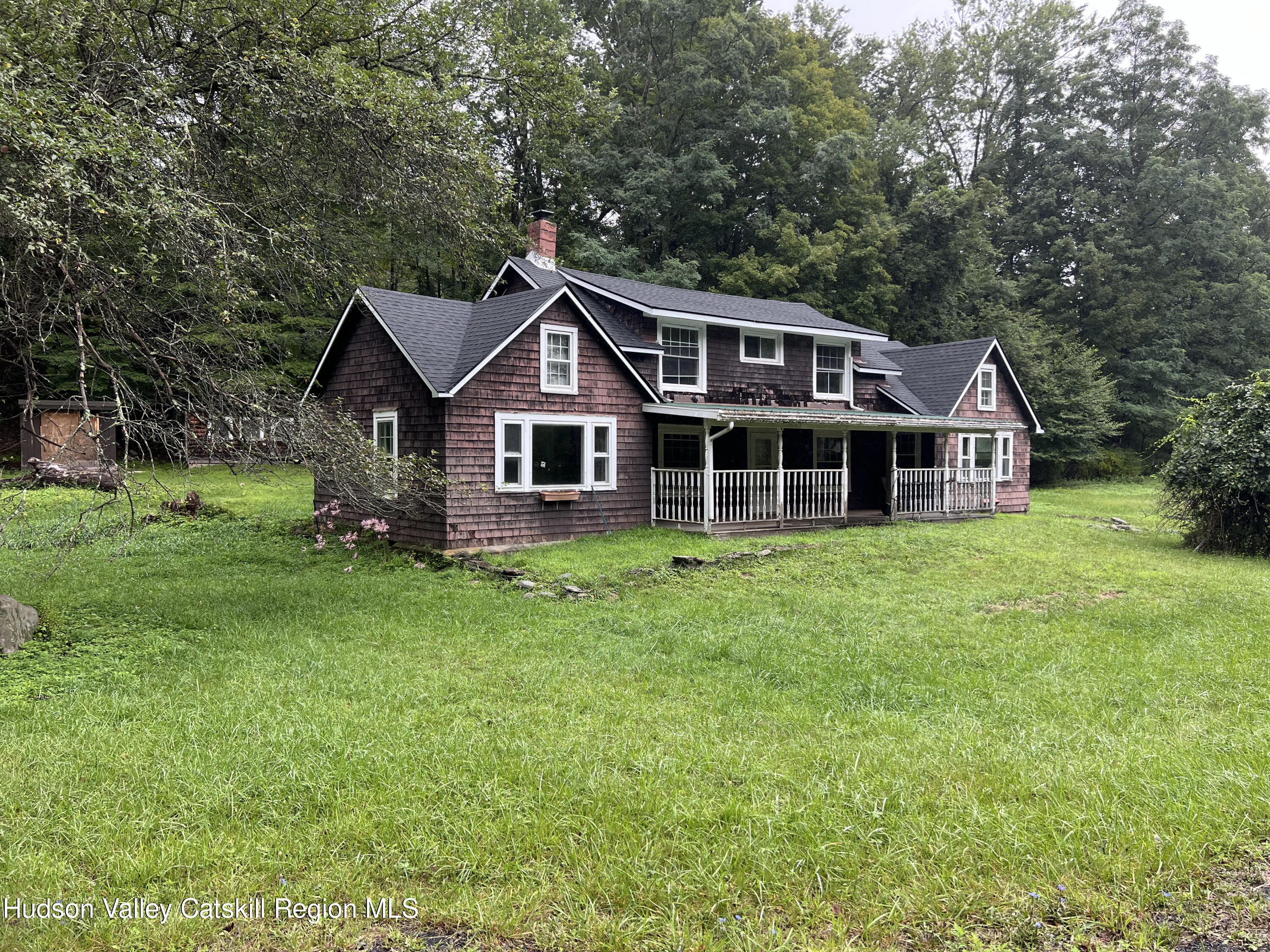 a front view of a house with a garden and trees