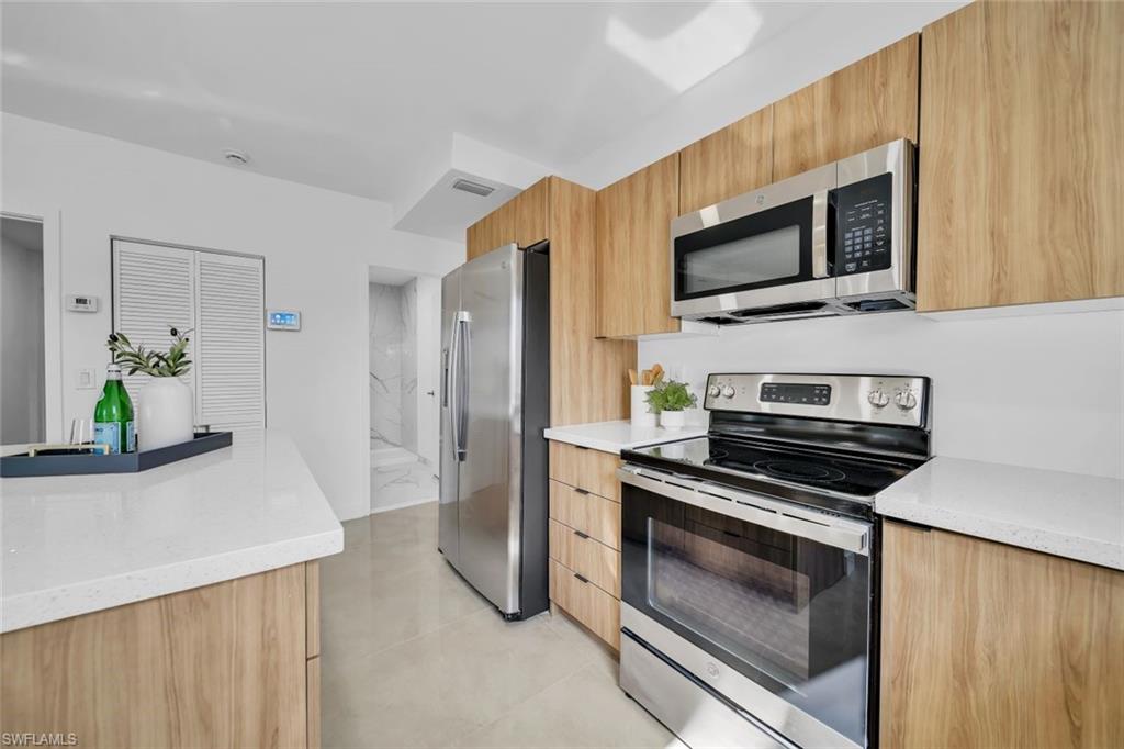 Kitchen featuring stainless steel appliances, light stone countertops, and light tile patterned flooring