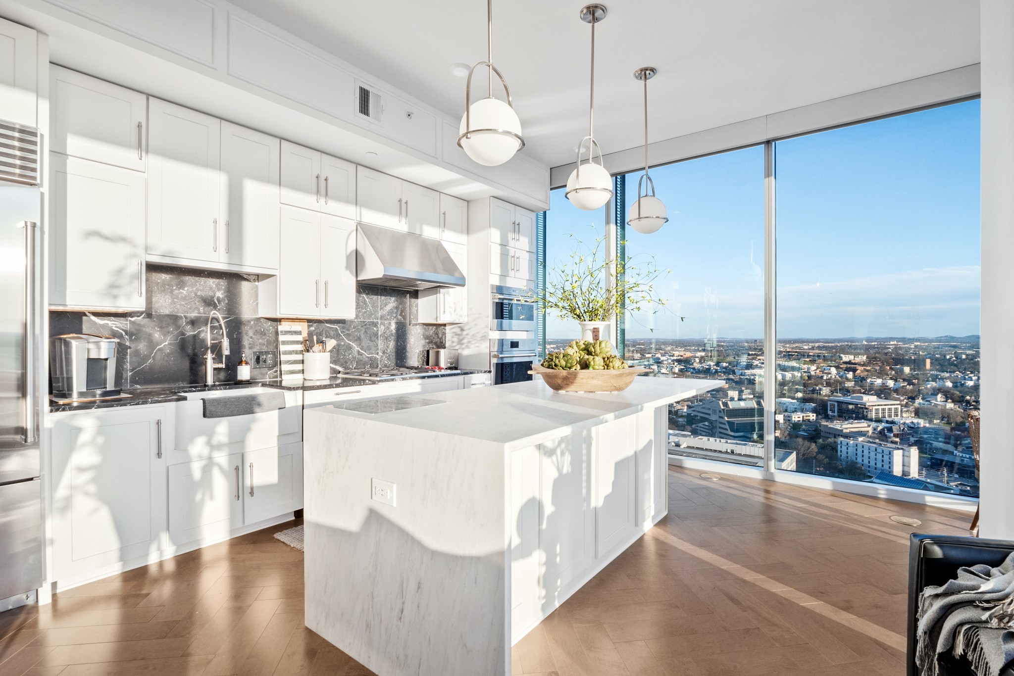 a large white kitchen with a large window and stainless steel appliances