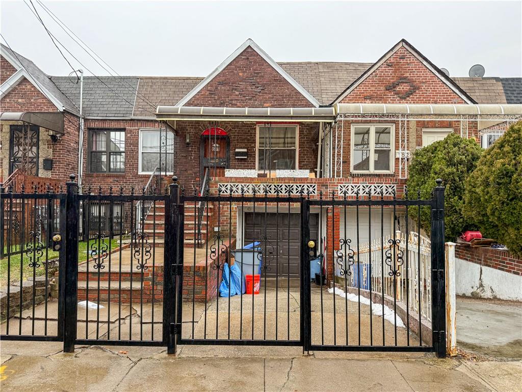 a view of a brick house with large windows and wooden fence