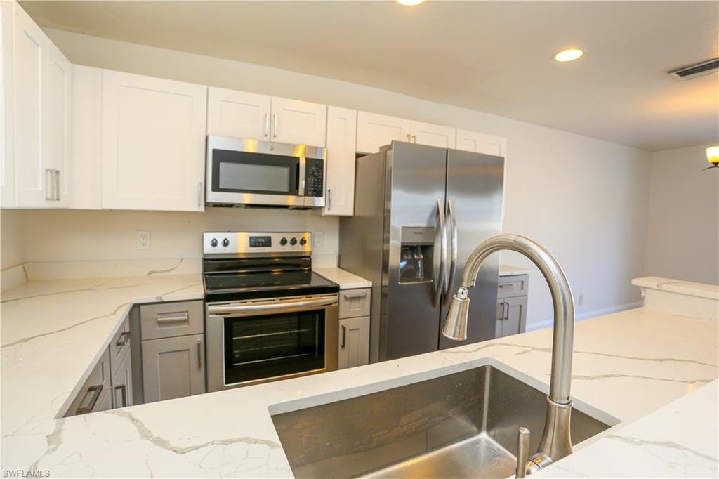 a kitchen with stainless steel appliances granite countertop a stove a sink and a microwave