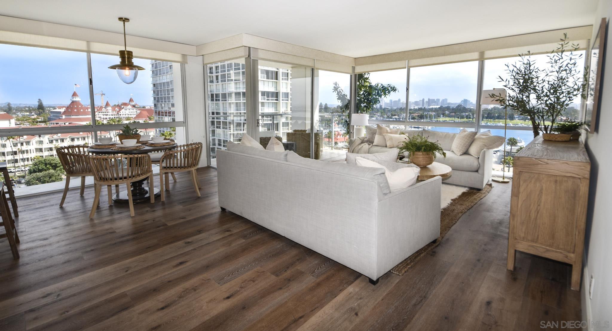 a living room with furniture large windows and wooden floor