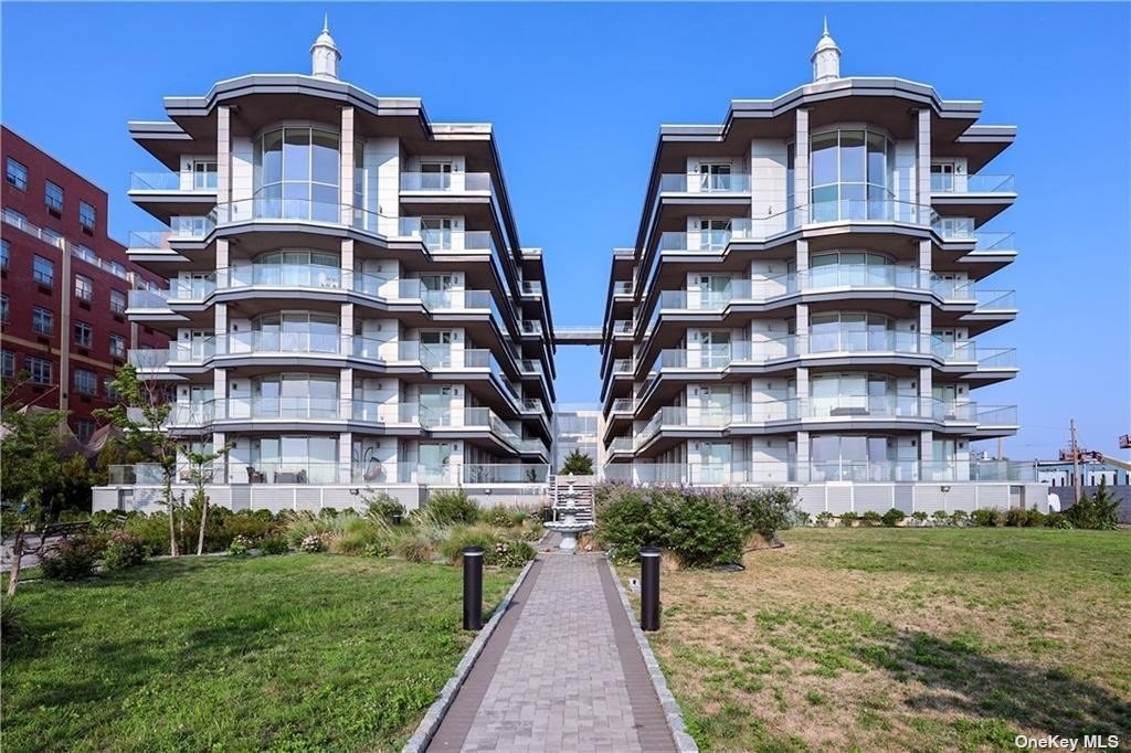 a front view of multi story residential apartment building with yard and parking space