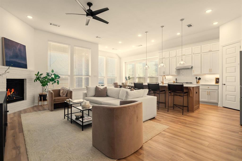 a living room with couches kitchen view and a fireplace