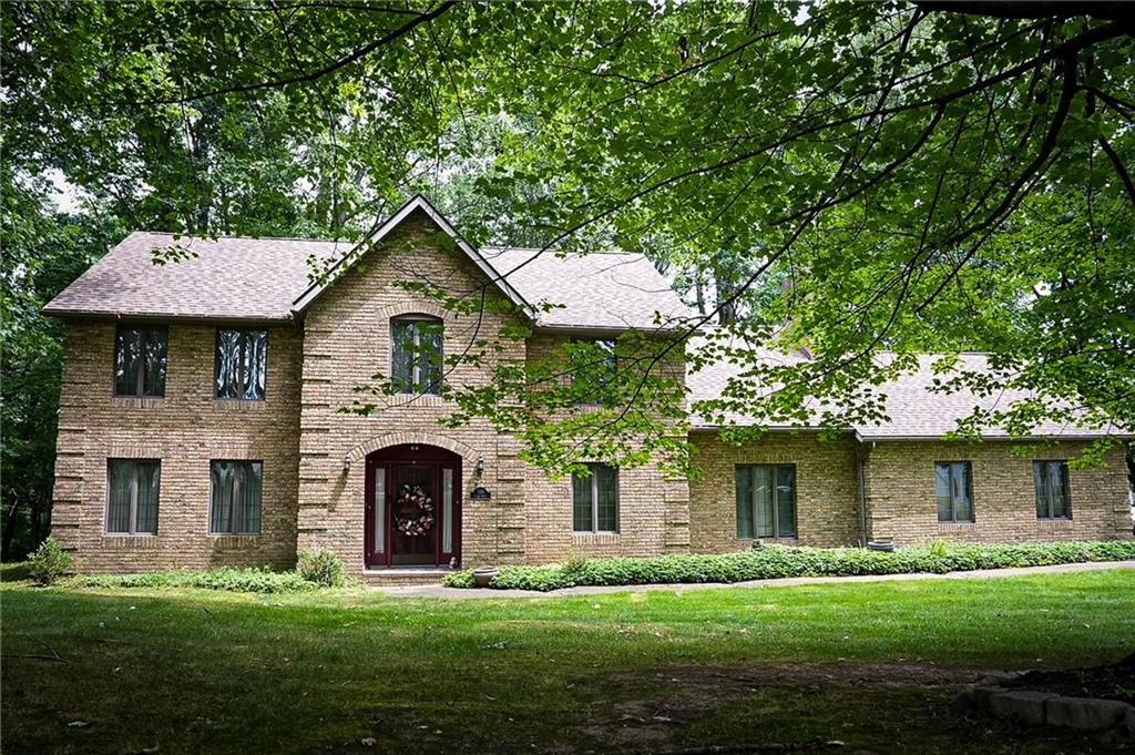 a front view of a house with a garden and trees