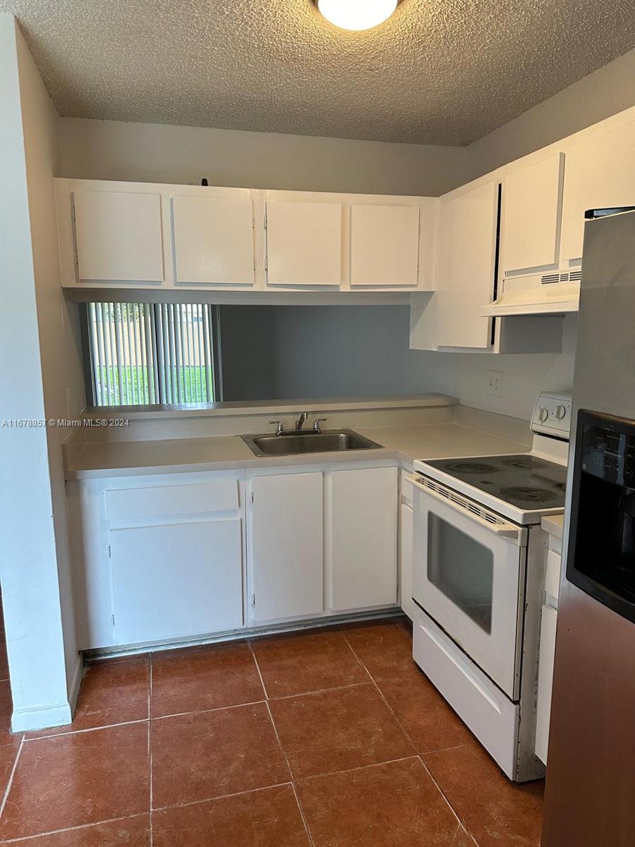 a kitchen with granite countertop a stove a sink and dishwasher with white cabinets