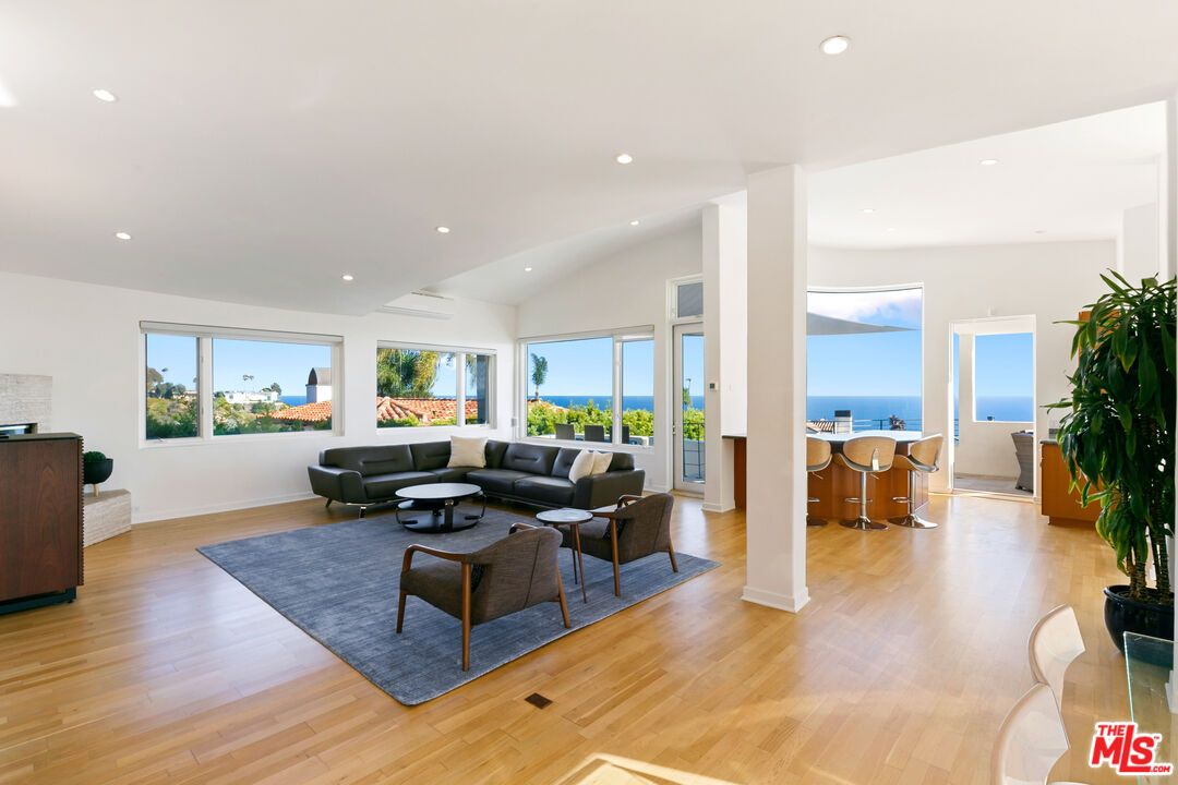 a living room with furniture kitchen view and a wooden floor