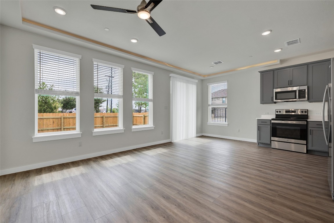 a view of kitchen with microwave a stove and a wooden floor