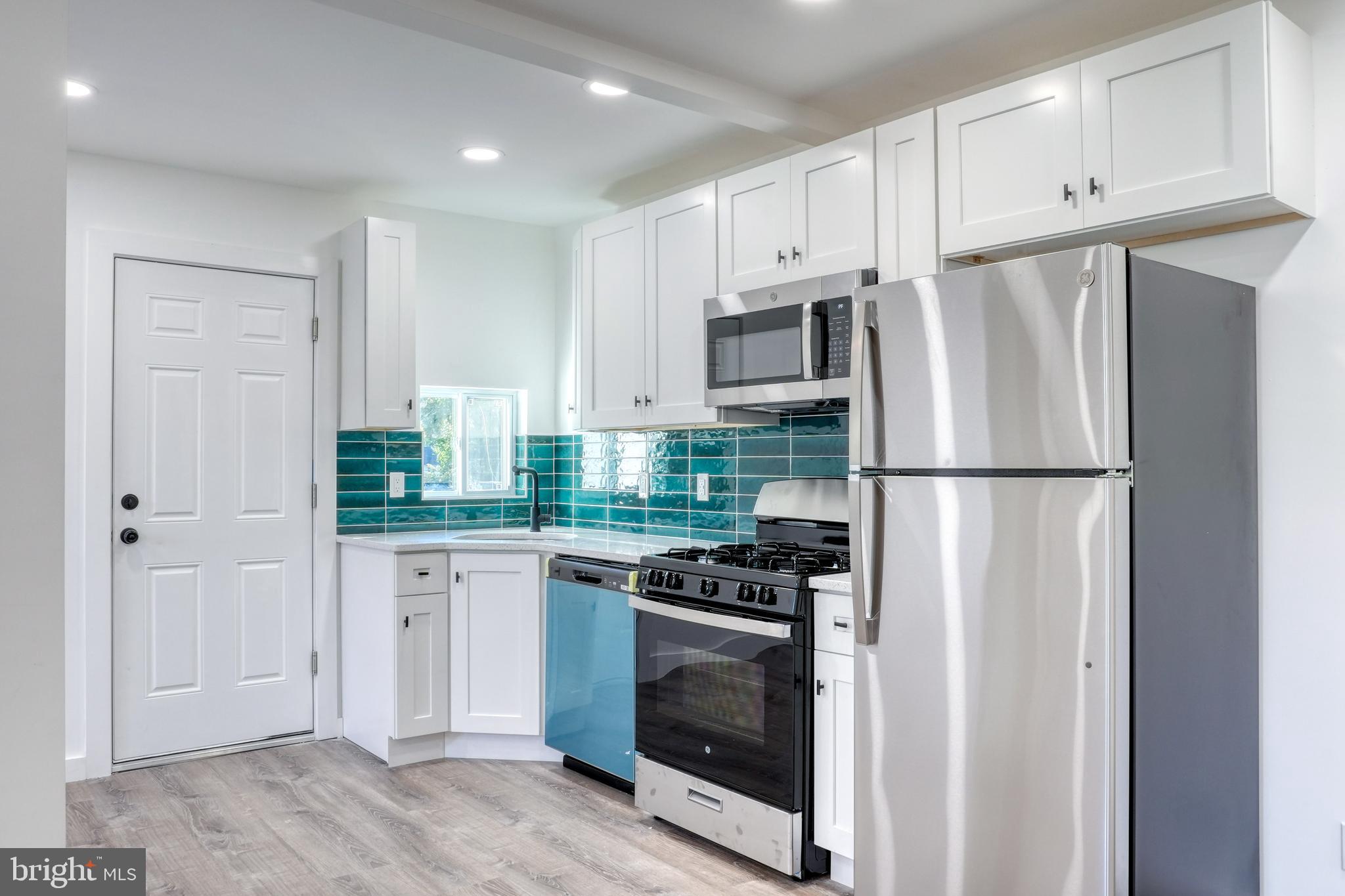 a kitchen with stainless steel appliances granite countertop a refrigerator a stove a sink and white cabinets