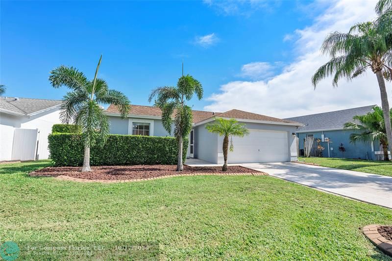 a front view of a house with a yard and palm trees