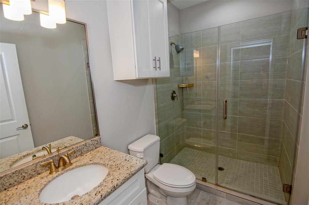 a bathroom with a granite countertop sink toilet a mirror and shower