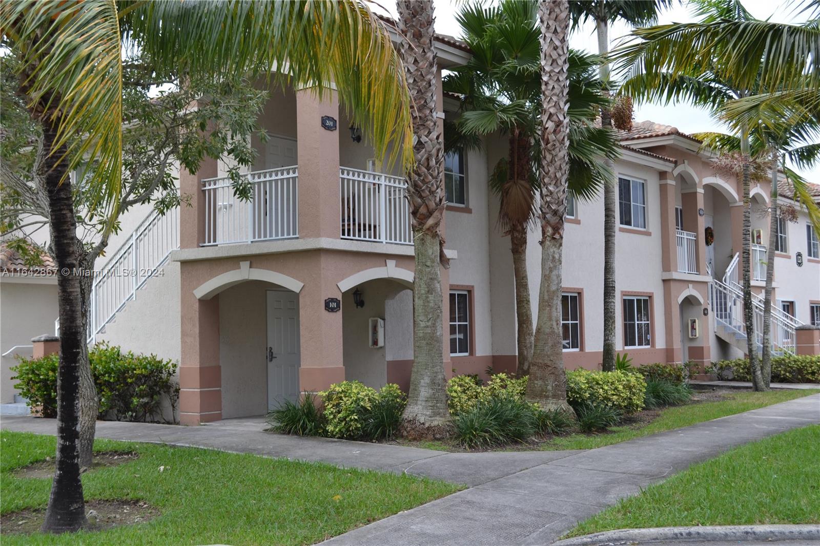 front view of house with a yard and palm trees