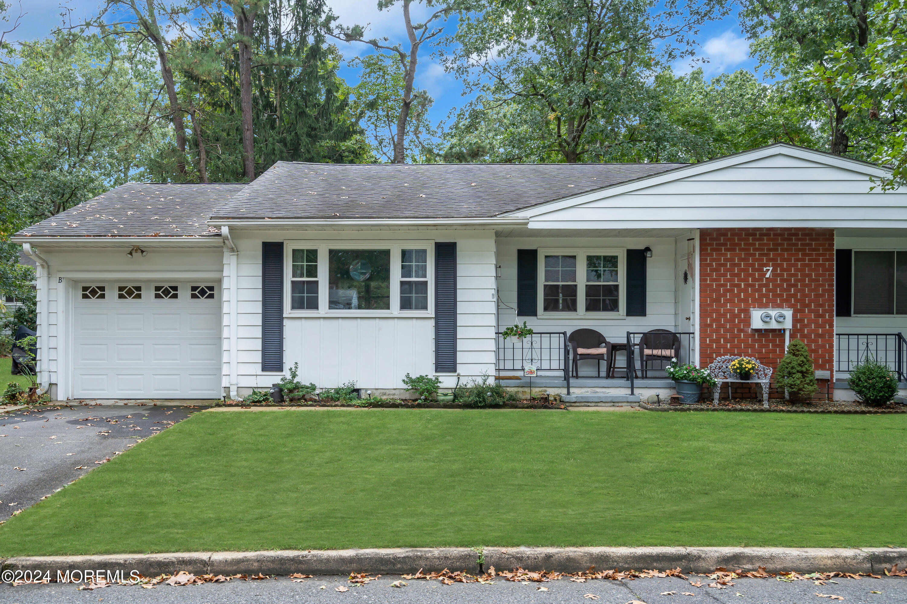 a front view of a house with garden and trees